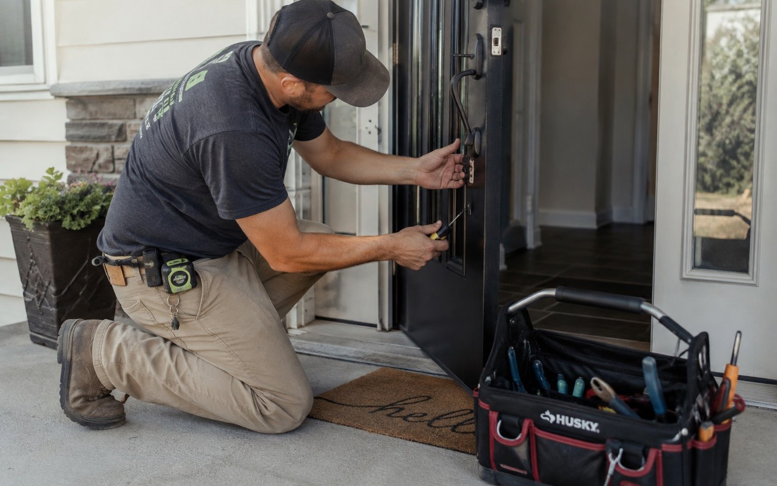 Handyman on a front porch installing hardware on an entry door